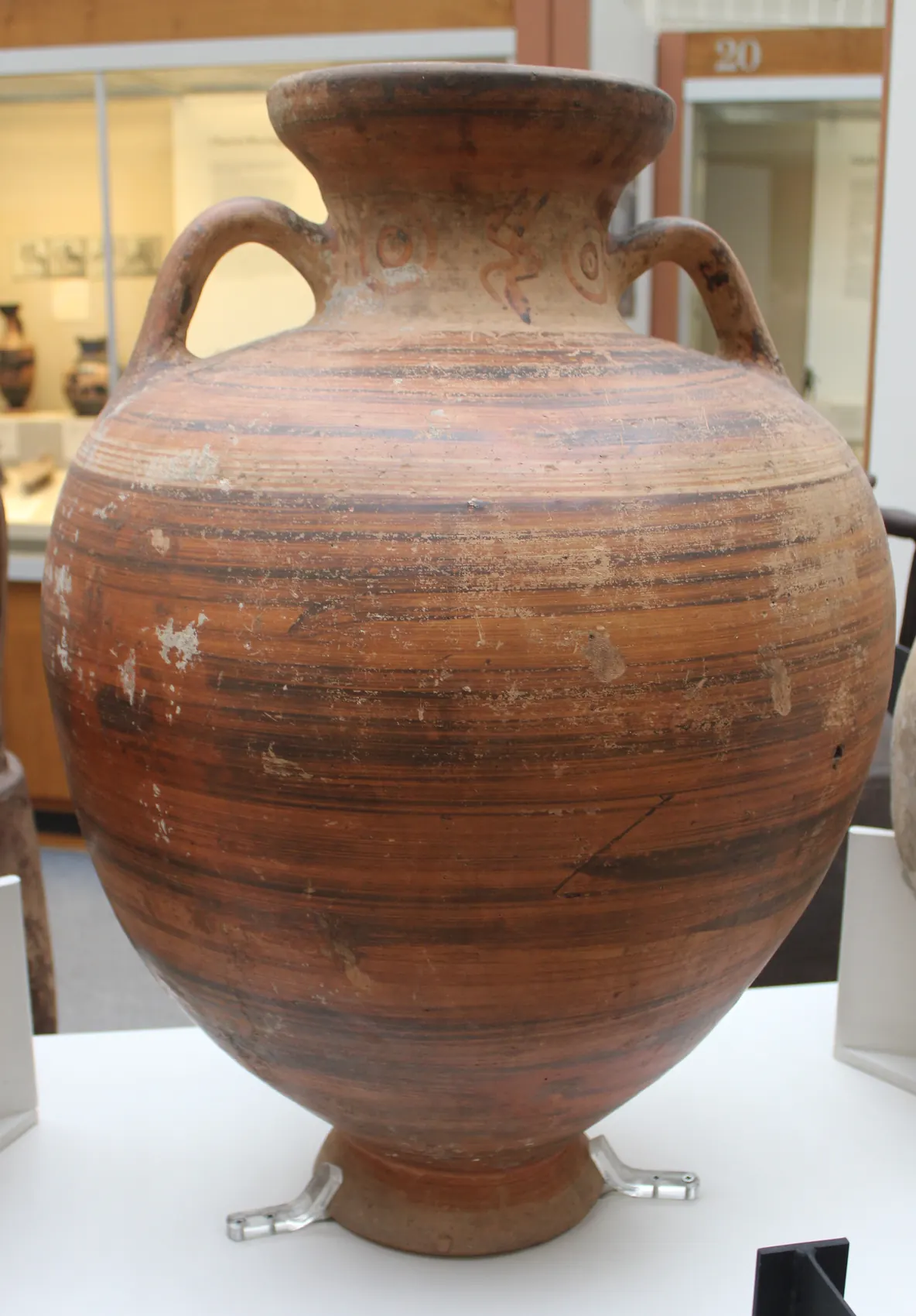 A large two-handled storage jar banded in dark slip, with circles and zigzag lines painted on its neck