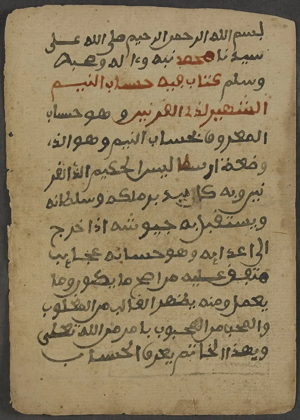 Manuscript page in black and red Arabic script on worn paper